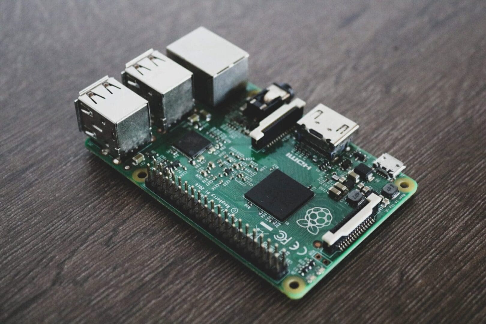A Raspberry Pi single-board computer rests on a dark wooden surface.